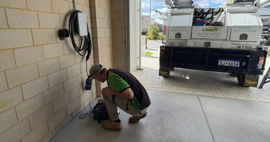 EVCI licensed electrician testing a wall-mounted EV charger installation in a Perth home garage